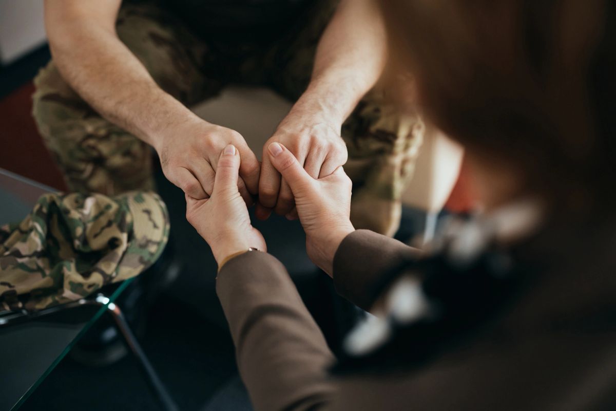 A veteran holding hands with a counselor in a moment of support